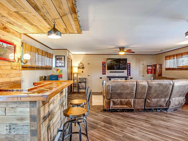 interior space with ceiling fan, wood-type flooring, wooden walls, and butcher block countertops