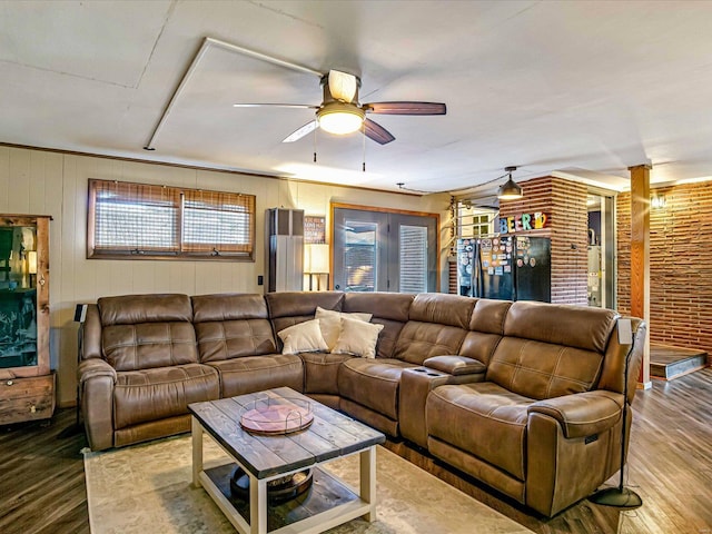 living room with hardwood / wood-style floors, ceiling fan, and brick wall