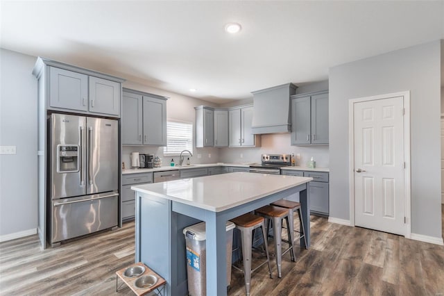 kitchen featuring custom exhaust hood, a kitchen island, stainless steel appliances, a breakfast bar area, and dark hardwood / wood-style flooring