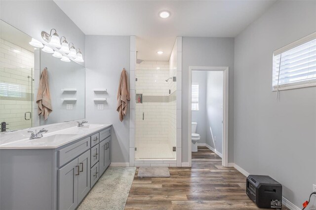 bathroom featuring vanity, a shower with shower door, hardwood / wood-style floors, and toilet