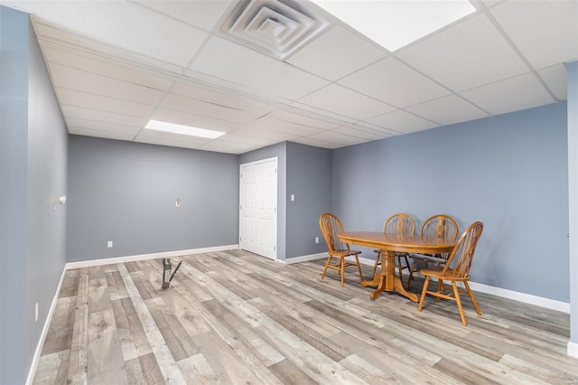 dining area with a paneled ceiling and light hardwood / wood-style flooring