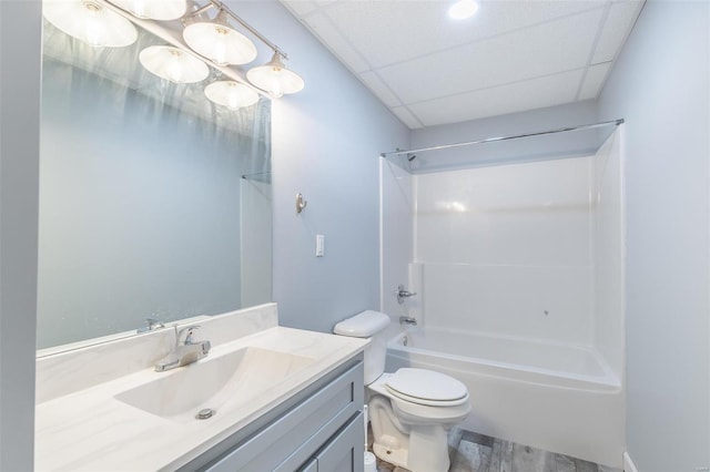 full bathroom with vanity, a drop ceiling, hardwood / wood-style flooring, toilet, and shower / tub combination