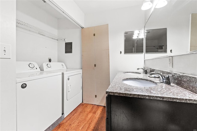 laundry room with light hardwood / wood-style flooring, washing machine and dryer, electric panel, and sink