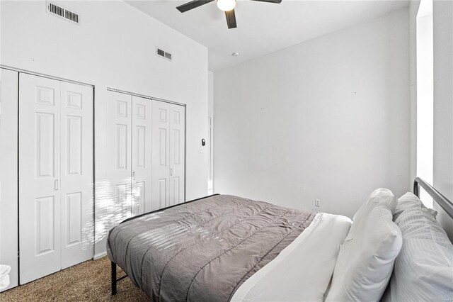 bedroom featuring carpet, ceiling fan, and multiple closets