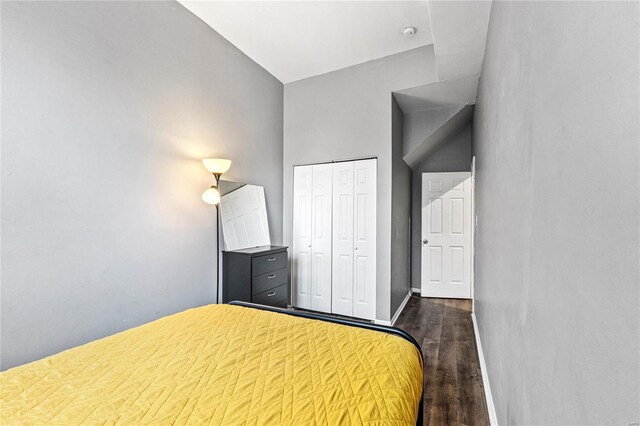 unfurnished bedroom featuring a closet, dark wood-type flooring, and high vaulted ceiling