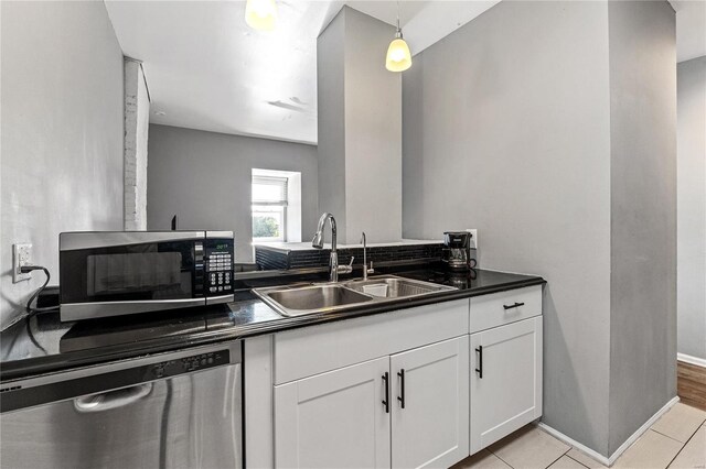 kitchen featuring white cabinetry, light tile patterned floors, stainless steel appliances, decorative light fixtures, and sink