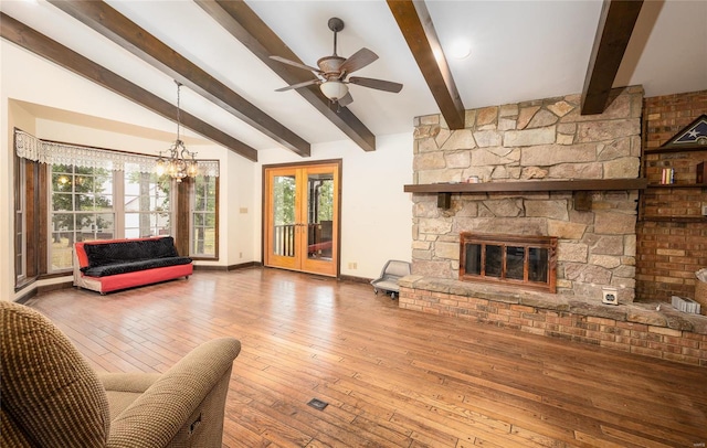 living room with hardwood / wood-style floors, ceiling fan with notable chandelier, a fireplace, and lofted ceiling with beams