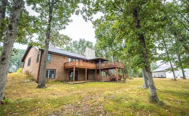 back of property with brick siding, a chimney, a lawn, a deck, and stairs