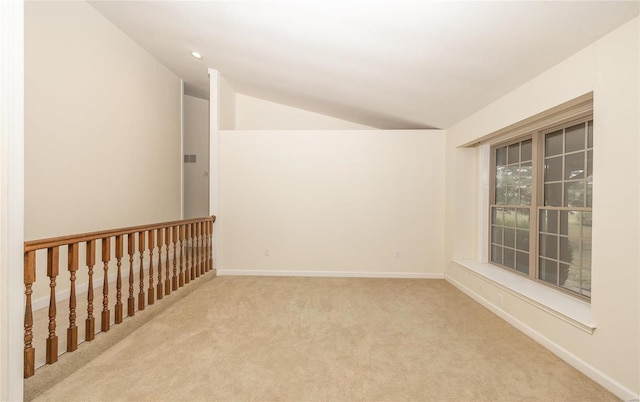 empty room featuring lofted ceiling, carpet floors, and baseboards