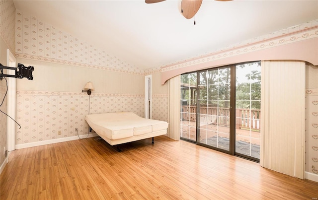 unfurnished bedroom with wallpapered walls, baseboards, light wood-style flooring, access to exterior, and vaulted ceiling