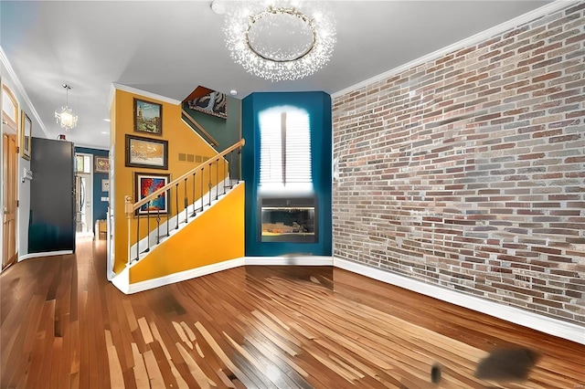 interior space with a notable chandelier, wood-type flooring, and ornamental molding