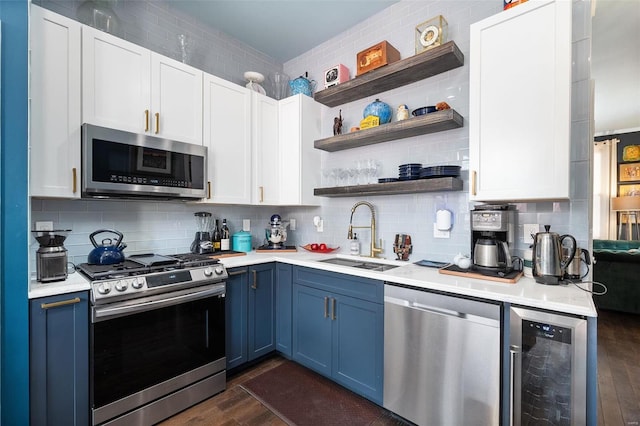 kitchen featuring blue cabinetry, sink, dark wood-type flooring, wine cooler, and appliances with stainless steel finishes