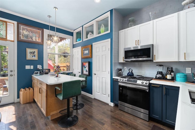 kitchen featuring white cabinets, dark hardwood / wood-style floors, stainless steel appliances, and hanging light fixtures