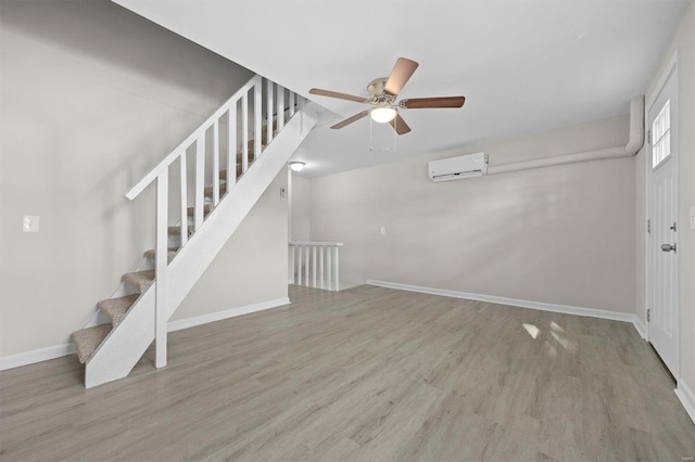 unfurnished living room featuring a wall mounted AC, ceiling fan, and wood-type flooring