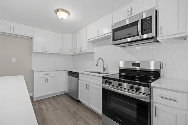 kitchen featuring light wood-type flooring, white cabinetry, tasteful backsplash, sink, and appliances with stainless steel finishes