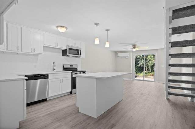 kitchen with appliances with stainless steel finishes, hanging light fixtures, ceiling fan, light wood-type flooring, and white cabinets