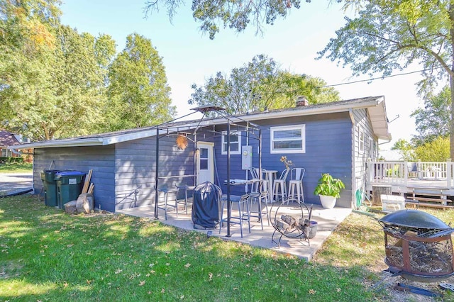 back of property with a patio, a deck, a lawn, and a fire pit