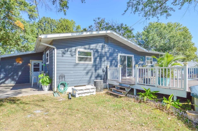 back of house featuring a patio, a lawn, and a wooden deck