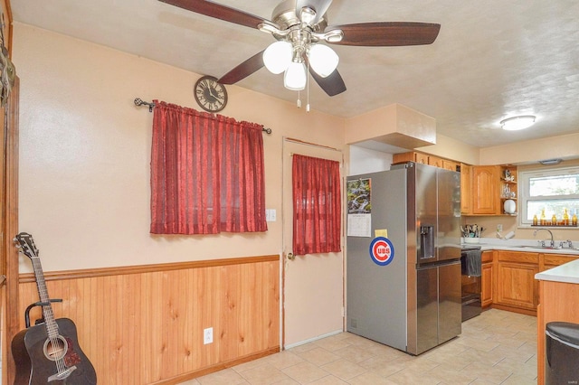 kitchen featuring sink, stainless steel fridge with ice dispenser, a textured ceiling, electric range, and wood walls