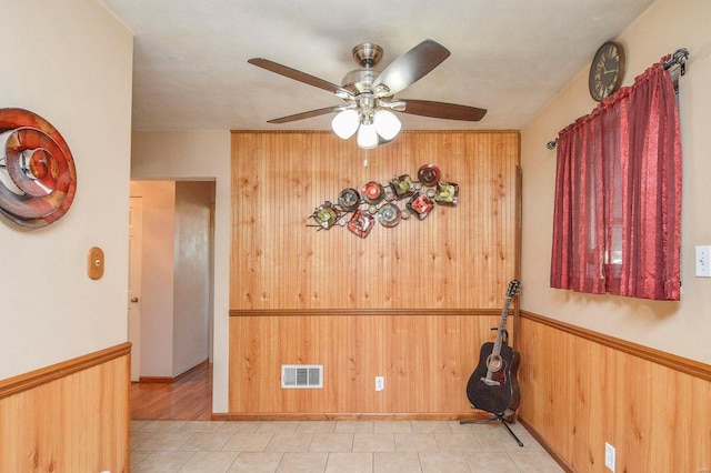 unfurnished dining area featuring wooden walls and ceiling fan