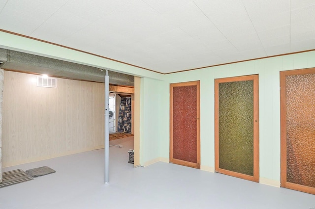 basement with ornamental molding and wooden walls