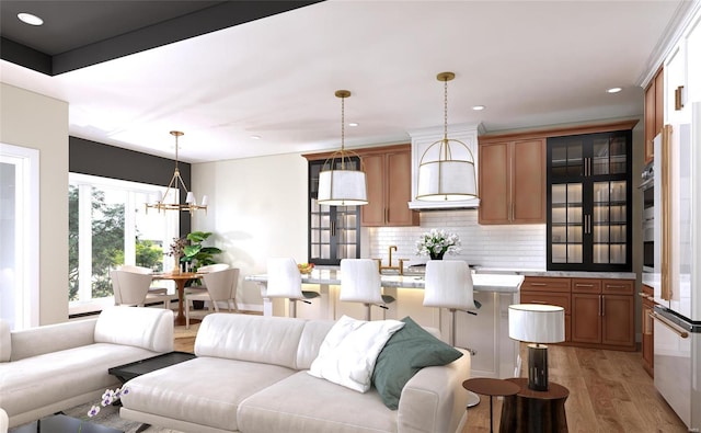 living room with an inviting chandelier, sink, and light hardwood / wood-style flooring