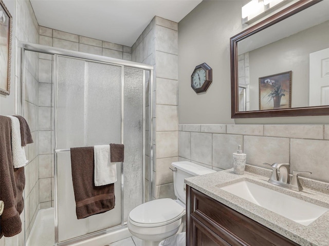 bathroom featuring vanity, an enclosed shower, tile patterned floors, tile walls, and toilet