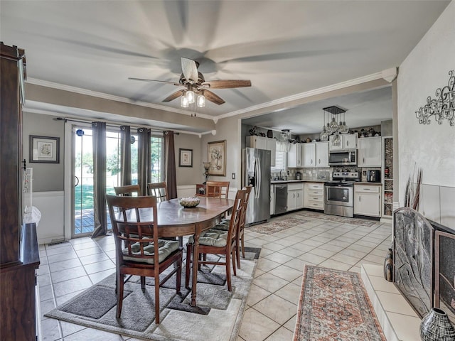 dining space featuring ceiling fan, sink, crown molding, and light tile patterned floors