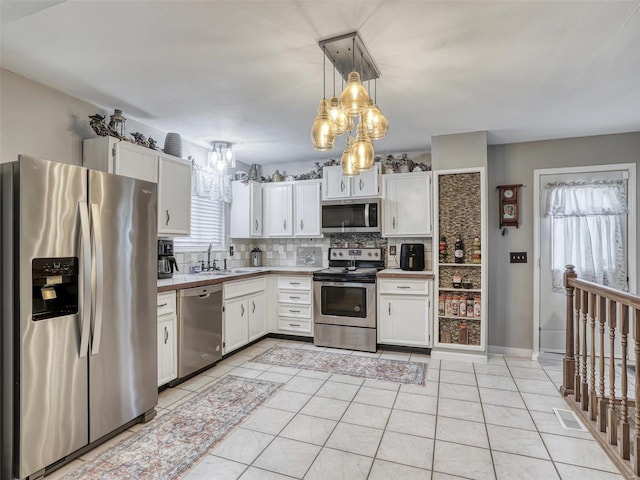 kitchen with pendant lighting, sink, white cabinetry, decorative backsplash, and appliances with stainless steel finishes