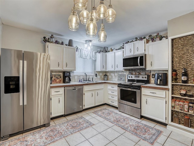 kitchen featuring appliances with stainless steel finishes, hanging light fixtures, sink, and white cabinets