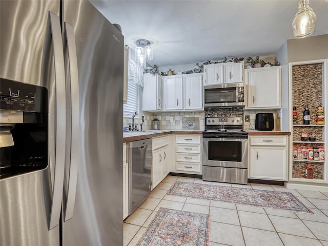 kitchen with light tile patterned flooring, sink, white cabinetry, hanging light fixtures, and appliances with stainless steel finishes