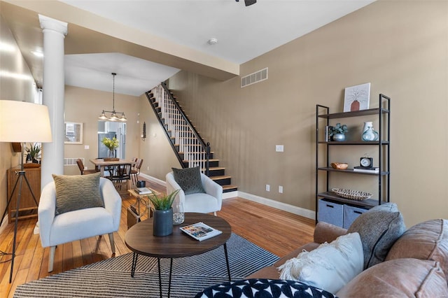 living room featuring light hardwood / wood-style flooring, ornate columns, and an inviting chandelier