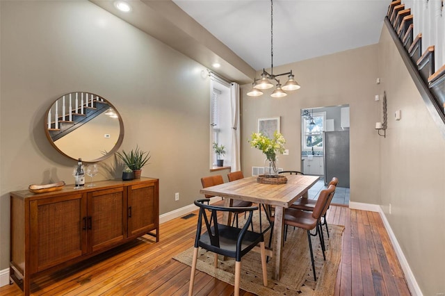 dining area featuring sink, a chandelier, and light hardwood / wood-style flooring