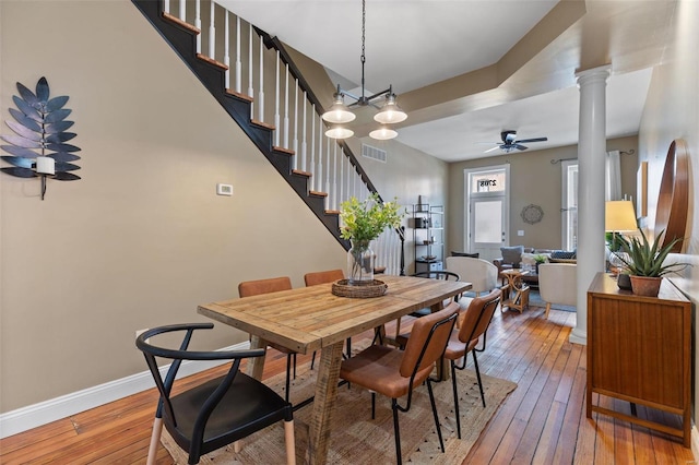 dining area with ceiling fan with notable chandelier, wood-type flooring, and decorative columns