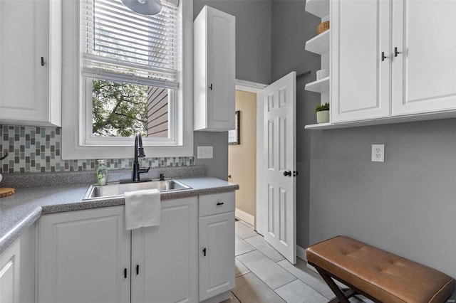 kitchen with light tile patterned floors, white cabinetry, and sink