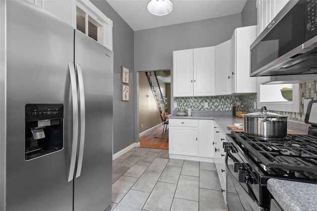 kitchen with white cabinets, backsplash, light tile patterned floors, and stainless steel appliances