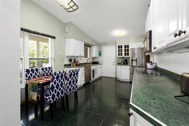 kitchen with sink, white cabinetry, appliances with stainless steel finishes, vaulted ceiling, and decorative backsplash