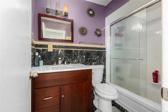 full bathroom featuring combined bath / shower with glass door, vanity, and toilet