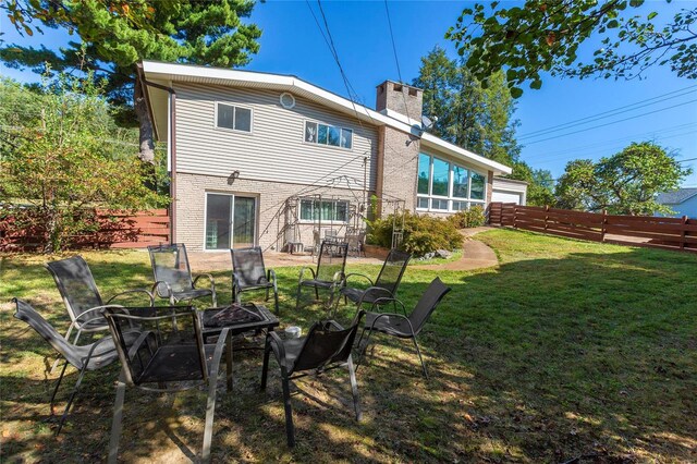 back of property with a fire pit, a sunroom, and a lawn