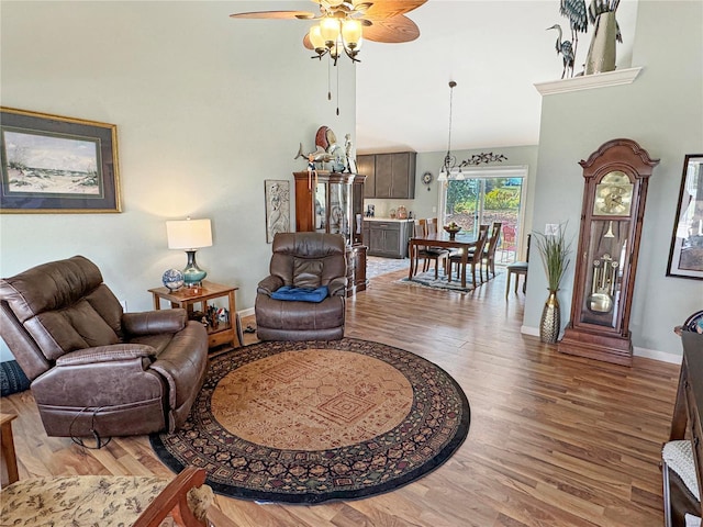 living room with ceiling fan, a towering ceiling, and hardwood / wood-style floors