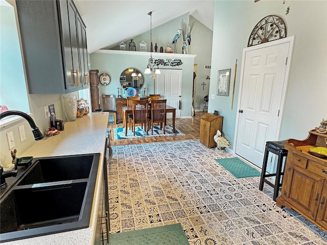 kitchen with pendant lighting, sink, a chandelier, high vaulted ceiling, and hardwood / wood-style flooring