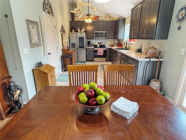 dining space featuring ceiling fan, sink, and vaulted ceiling