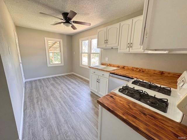 kitchen with light wood-type flooring, a textured ceiling, white cabinetry, white dishwasher, and ceiling fan