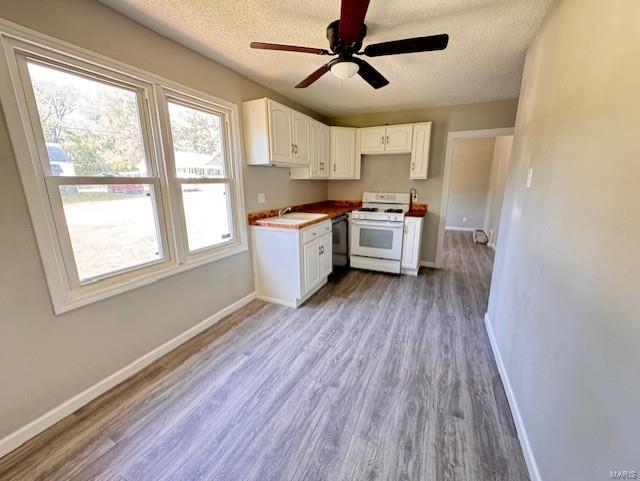 kitchen with white cabinets, dishwasher, wood-type flooring, ceiling fan, and white gas stove