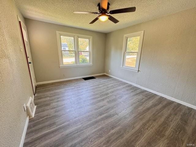 empty room with ceiling fan, a textured ceiling, and dark wood-type flooring