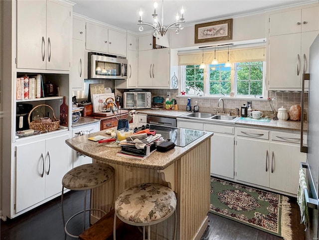 kitchen featuring a kitchen bar, a kitchen island, sink, hanging light fixtures, and white cabinets