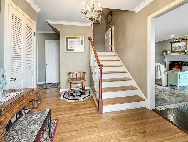 staircase with crown molding, an inviting chandelier, and hardwood / wood-style flooring