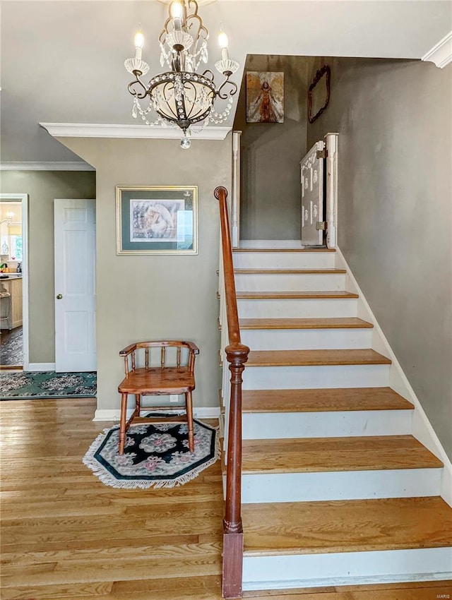 stairs featuring crown molding, a chandelier, and hardwood / wood-style floors