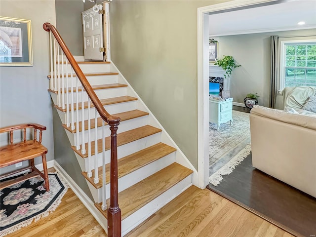 staircase featuring a high end fireplace and wood-type flooring