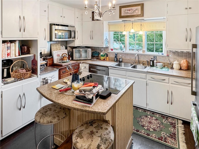 kitchen with white cabinets, an inviting chandelier, decorative light fixtures, appliances with stainless steel finishes, and sink